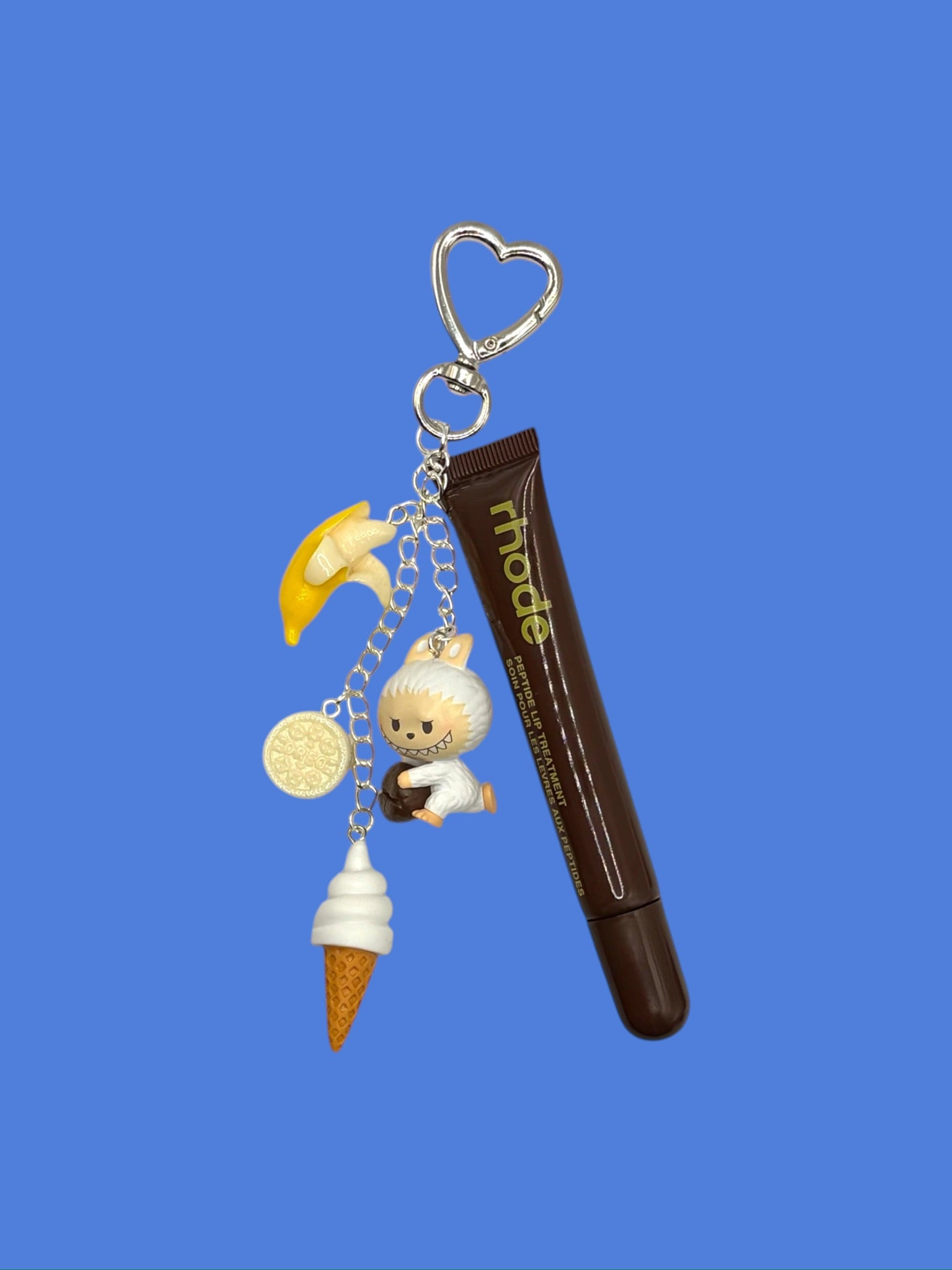 Rhode Lip Treatment Charm Keychain with ice cream cone, banana, figurine, and coin charms on a silver heart clasp